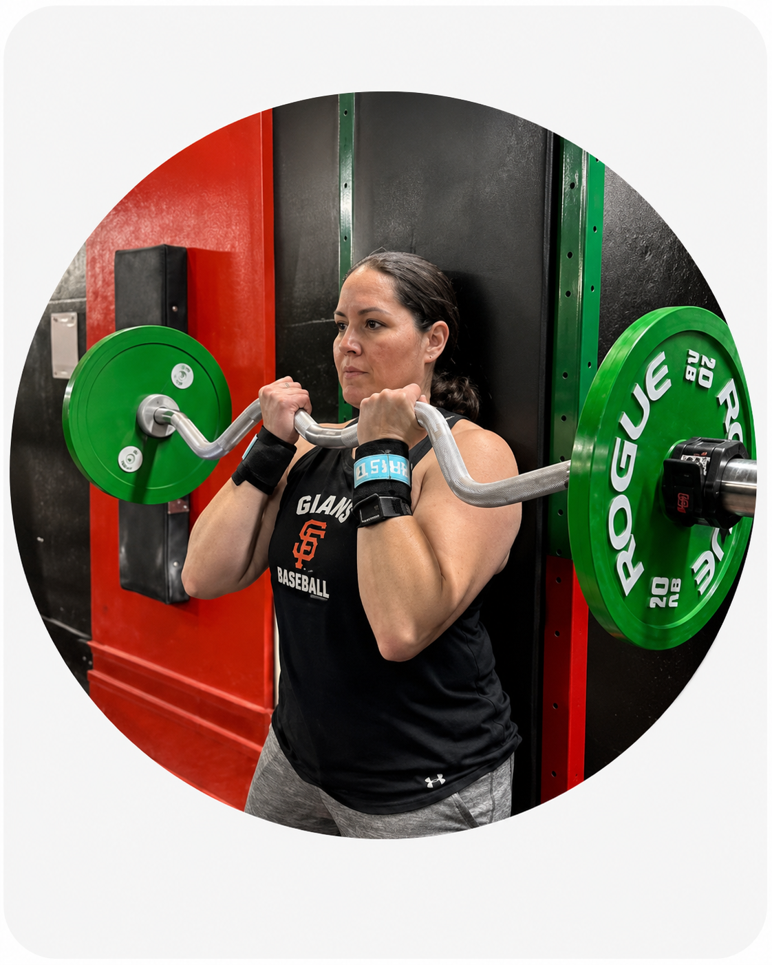 A member holding a loaded EZ bar at the top of a curl at Age-Less Strength Gym