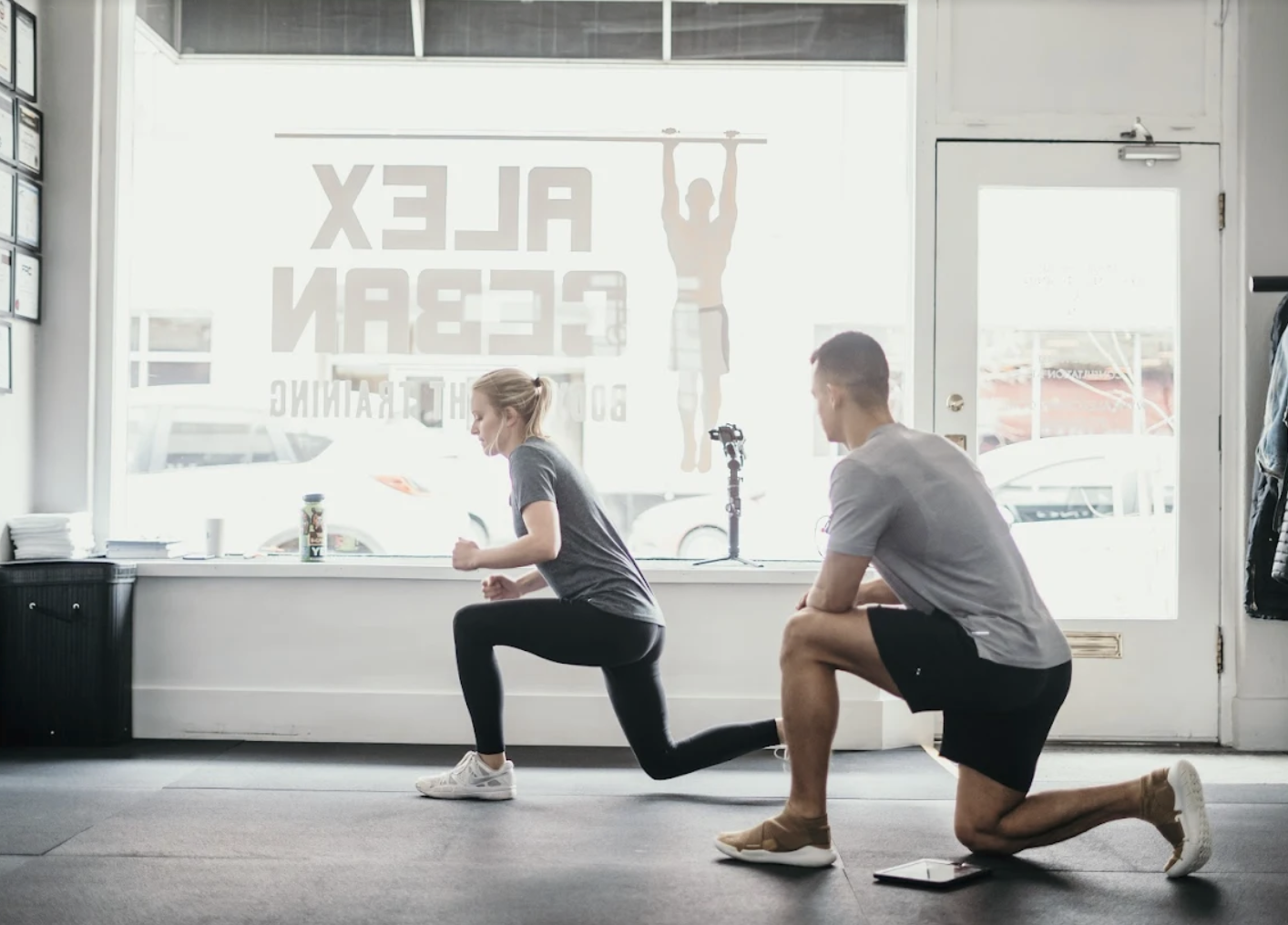Coach watching a client perform a split squat inside a Capra Bodyweight Training studio