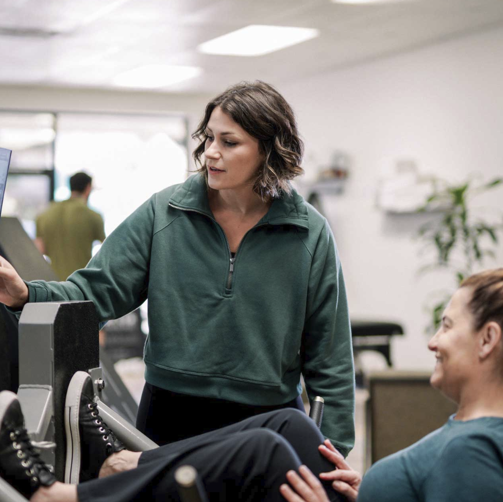 A coach adjusting the ARX console as a seated client smiles at Top Tyr Training