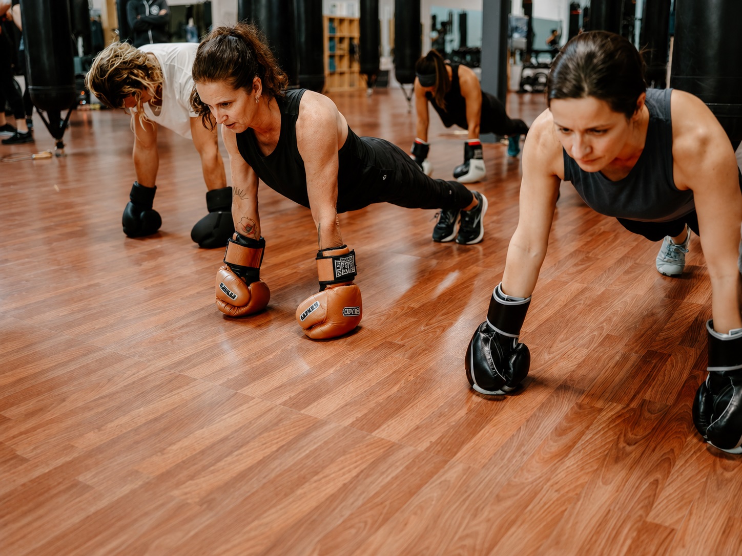 Participants in boxing gloves holding a high plank on the Westside Fitboxing studio floor